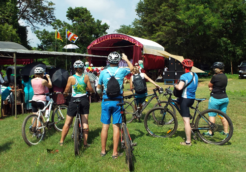 group of cyclist enjoy on their way with local community and stop at village Ceremony in Sri Lanka 